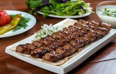 Fast food. Eastern food. Shish kebab, lyulya-kebab. Dishes of oriental cuisine lying in plte and decorated with greens and vegetables, sauces
