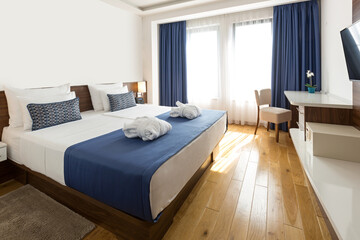 Interior of a hotel bedroom with blue curtains in the morning