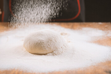 Baker pours flour for making pizza. Chef cooking dough to bake a cake on a wooden table. The process of making home baking. Cooking pasta, bread,spaghetti,khachapuri, food concept