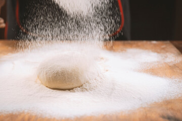 Baker pours flour for making pizza. Chef cooking dough to bake a cake on a wooden table. The process of making home baking. Cooking pasta, bread,spaghetti,khachapuri, food concept