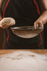 Baker pours flour for making pizza. Chef cooking dough to bake a cake on a wooden table. The process of making home baking. Cooking pasta, bread,spaghetti,khachapuri, food concept