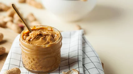 Foto op Plexiglas Glass jar of homemade peanut butter on kitchen table banner with space for design © Виктория Попова