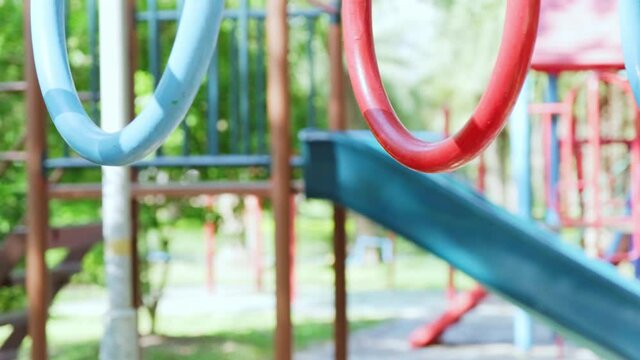 Happy little girl having fun on colorful bar at outdoor playground. Active kid hang on colorful monkey bars in the park. Play is learning in childhood. close-up hand