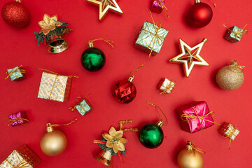 Flat lay, Christmas decorations composition on a red background: Red, gold and green ball ornaments, presents, gifts and Christmas star