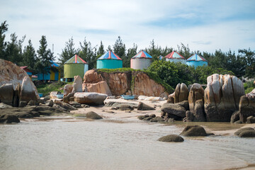 View from the water to the beach with large stones and colorful stalls. Colorful houses by the sea. High quality photo