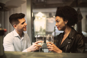 Romantic multiracial couple drinking white wine at restaurant counter