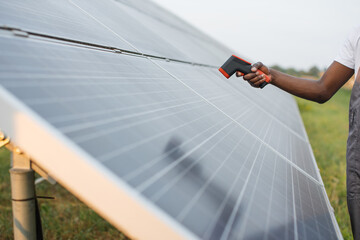 Close up of male hand holding electronic thermal imager near solar cell outdoors. African american...