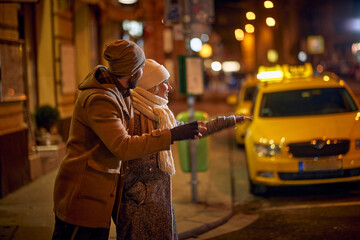 Man and woman in night  street calling taxi.