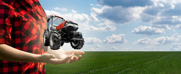 Woman farmer holds a virtual tractor on a background of a green agricultural field.