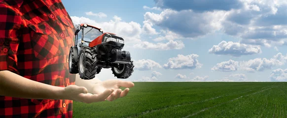 Poster Vrouw boer houdt een virtuele tractor op een achtergrond van een groen landbouwveld. © scharfsinn86