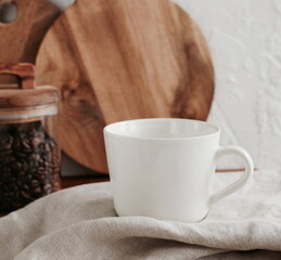 Coffee mug mockup on the beige linen tablecloth in the modern kitchen interior . copy space.Business food brand template.