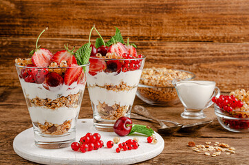 Granola with fresh berries and yogurt on wooden background, copy space. Healthy breakfast and diet concept