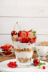 Healthy dessert of granola with yogurt and fresh berries on white wooden background. Copy space