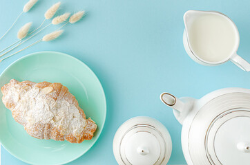 Morning table. Fresh croissants on turquoise plates and milk on pastel blue background. Top view,...