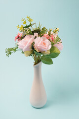Vase with colorful flowers on a light blue background. Spring, romantic decoration