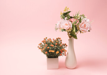 Various flower plants laying on a table top against pastel pink background. Minimal decoration concept.