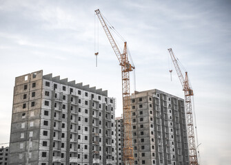 Two tall buildings under construction with cranes