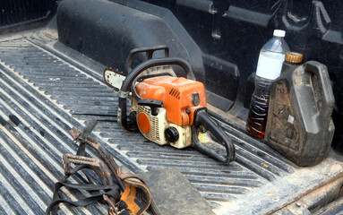 An old chainsaw is in the back of a pickup truck