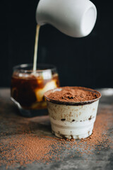 Traditional italian dessert tiramisu in a glass on a dark background.