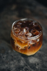 Iced coffee americano with milk in a glass at dark background