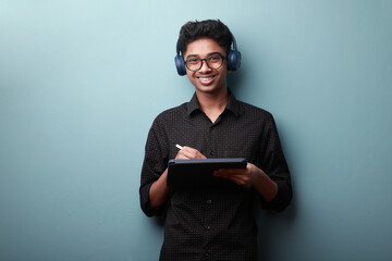 Portrait of a smiling young boy of Indian ethnicity holding a tablet phone in hand 