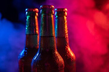 Three bottles of beer in a blue-pink mist.