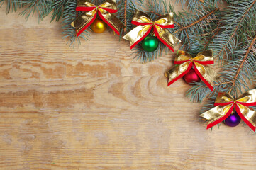 Christmas background. Wooden texture, spruce branches and Christmas balls with bows. 