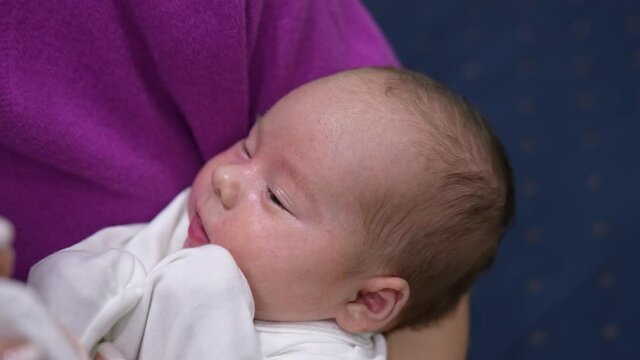 Tiny child in mother&rsquo;s hands opens mouth waiting for bottle. Mother gives him a bottle and baby takes it hungrily and eats and closes his eyes slowly. Close up.