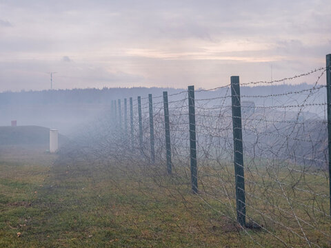 Rows of barbed wire on the state border. The separation of the two countries. Foggy autumn landscape 