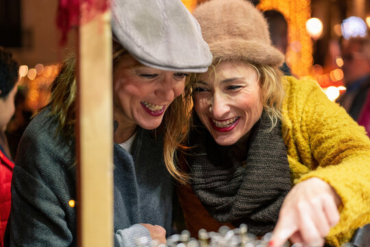 40s women having fun shopping at the craftsmarket - two best friends buying gift at Christmas market - Powered by Adobe
