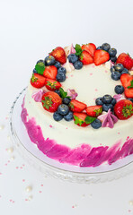 Delicate cake decorated with fresh berries strawberries blueberries white plain background. Festive dessert with berries