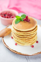baking American pancakes with red berry currants on a pink background