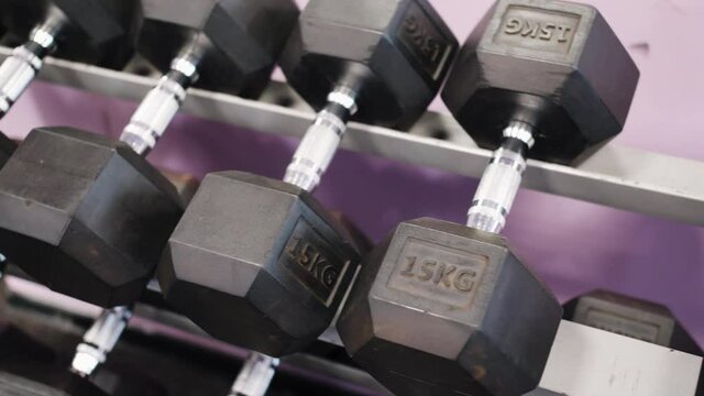 CLOSE-UP: panorama of multi-weight dumbbells stacked on a rack in the gym. Heavy sports equipment for strength training. Concept of a healthy lifestyle.