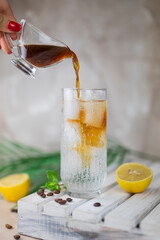 girl the bartender pours espresso coffee with lemon into the tonic