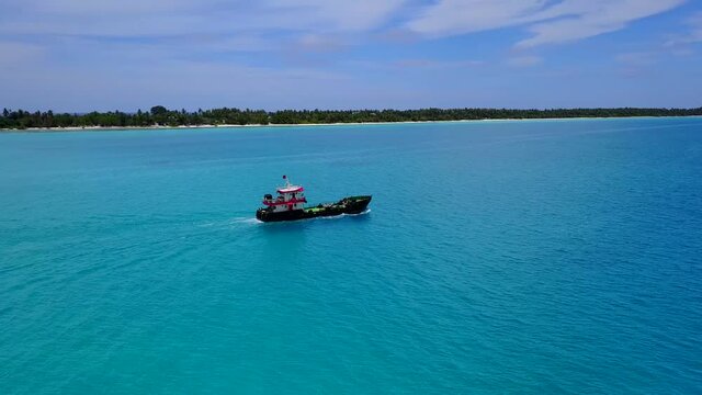 Aerial view of Cargo ship. Large ship at sea near the tropical island in Maldives. Aerial top down. Sunny sumer day.