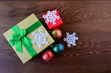 Beautiful gift box and Christmas decorations, balloons and snowflakes on wooden background. Preparation for New Year. Top view. Copy space