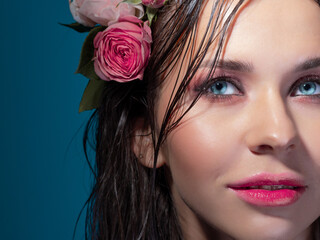 Fototapeta na wymiar A beautiful young brunette with bright blue eyes, in a Hawaiian image. Wet hair and flowers in the hairstyle