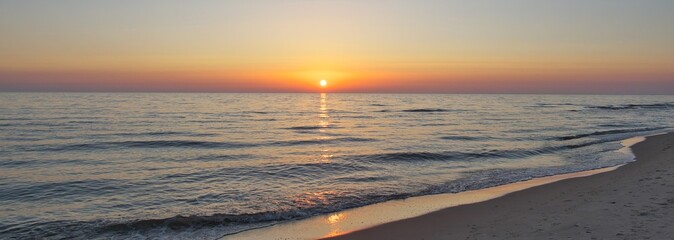 Calm seashore in the evening. Hazy sun at sunset. Panoramic photo. © Igor