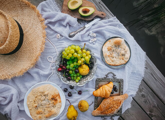 Picnic in vintage style, Fruits and bread with vintage dishes, decorations on a wooden background near the water, Top view, Selective focus