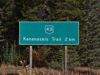 Close-up view of road sign with green color and white text showing the distance to Highway 40 (Kananaskis Trail) in Alberta, Canada in the Rockies.