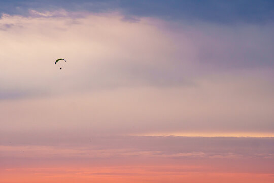 Silhouette of a paraplane (powered parachute) flying in magnificent pink evening sky. Balloon festival in Belgorod, Russia.