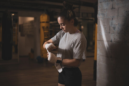 an underage girl putting bandages on her hands before putting on her boxing gloves.