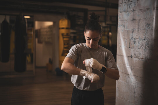 an underage girl putting bandages on her hands before putting on her boxing gloves.