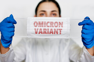 Female doctor holds a face mask with - Omicron variant text on it. Covid-19 new variant - Omicron....