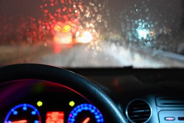 Dangerous winter season with snow on the road. The interior of the car from the driver's point of view - dangerous evening traffic in bad weather.