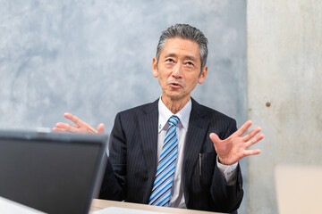 スーツで意見を述べる経営者