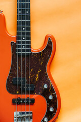 orange electric bass guitar on orange background with copy space