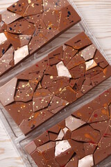 Craft handmade chocolate bars with color splashes on white wooden table. Top view. Copy space.