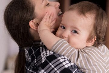 Portrait Adorable Face Of Little Cheerful Happy Toddler baby girl child With Charming Smile Look At Mom Strong Cuddles Loving Mommy Together. Mother Hugs play love care kiss smiling daughter at home