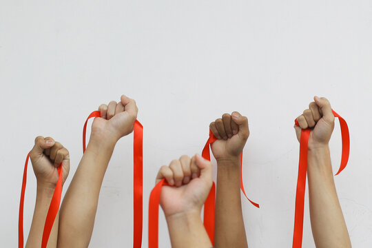 Close-up shot of people lift up their hands with red ribbon for AIDS awareness